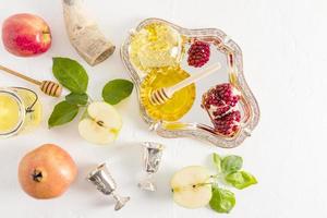 fond festif avec symboles traditionnels du nouvel an rosh hashanah. grenade, pommes, miel dans un bol en argent, une corne d'abondance. vue de dessus. photo