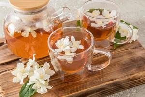 l'heure du thé. deux tasses modernes en verre et une théière avec du thé aromatique au jasmin sur la planche de bois d'origine. photo