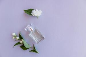 vue de dessus d'une bouteille en verre de parfum féminin ou d'eau de toilette avec des bourgeons et des fleurs de jasmin parfumé. une copie de l'espace. un modèle pour la vue. photo