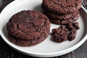 biscuits aux pépites de chocolat faits maison sur une plaque en céramique et un fond marron en bois. cuisson des aliments. photo