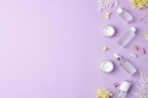 produits cosmétiques de soins de la peau avec des fleurs sur fond rose. mise à plat, espace de copie photo