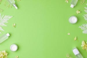 produits cosmétiques de soins de la peau avec des fleurs sur fond vert. mise à plat, espace de copie photo