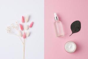 composition minimale avec des produits cosmétiques de soins de la peau et des fleurs sur fond rose. mise à plat. photo