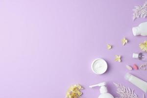 produits cosmétiques de soins de la peau avec des fleurs sur fond rose. mise à plat, espace de copie photo