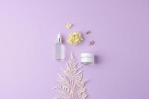 produits cosmétiques de soins de la peau avec des fleurs sur fond rose. mise à plat, espace de copie photo