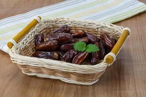 Dates fruits dans un panier sur fond de bois photo