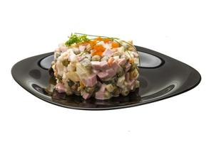 Salade russe sur l'assiette et fond blanc photo