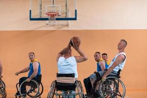 Anciens combattants handicapés de guerre mixtes et équipes de basket-ball d'âge en fauteuil roulant jouant un match d'entraînement dans une salle de sport. concept de réadaptation et d'inclusion des personnes handicapées photo