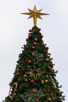 l'ornement étoile met au sommet du grand sapin de noël avec des boules colorées et d'autres ornements. photo