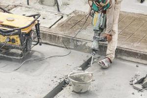 travailleur de la construction à l'aide d'un marteau-piqueur forant une surface en béton photo