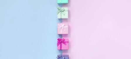 de petites boîtes cadeaux de différentes couleurs avec des rubans se trouvent sur un fond violet et rose photo