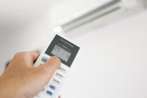 main avec télécommande dirigée sur le climatiseur à l'intérieur de la pièce photo