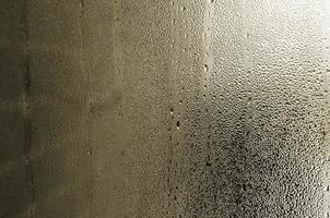 texture d'une goutte de pluie sur un fond transparent en verre humide. tonique en couleur jaune photo