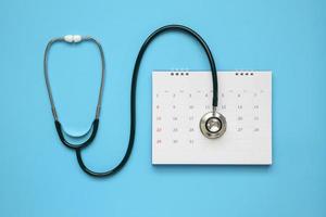 stéthoscope avec date de page de calendrier sur fond bleu concept médical de rendez-vous chez le médecin photo