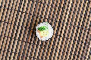 le rouleau de sushi est posé sur un tapis de couture en paille de bambou. cuisine asiatique traditionnelle. vue de dessus. minimalisme à plat tourné avec espace de copie photo