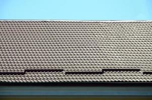 un fragment de toit d'une tuile métallique de couleur rouge foncé. toiture de qualité photo