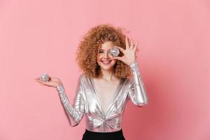 adorable fille aux boucles blondes vêtue d'un chemisier argenté sourit et pose avec des boules disco sur p photo