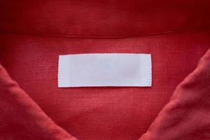 Étiquette d'étiquette de vêtements blanc vierge sur fond de texture de tissu de chemise en lin rouge photo