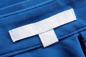 étiquette blanche de vêtements de soin de blanchisserie vierge sur fond de tissu bleu photo