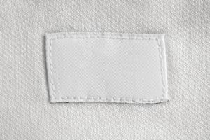 Étiquette de vêtements de soin de lessive blanc vierge sur fond de chemise en coton photo