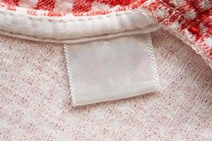 Étiquette de vêtements de soin de lessive blanc vierge sur fond de chemise en coton photo