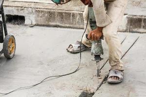 travailleur de la construction à l'aide d'un marteau-piqueur forant une surface en béton photo