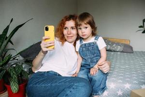 jeune mère et enfant prennent des photos ensemble à la maison, s'amusent