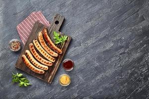 savoureuses saucisses de porc grillées aux épices et herbes sur une planche à découper en bois