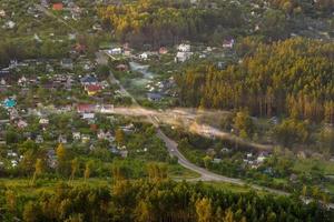 vue panoramique aérienne du village verdoyant avec maisons, granges et route de gravier en forêt photo