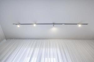 plafond suspendu avec lampes halogènes et construction de cloisons sèches dans une pièce vide d'un appartement ou d'une maison. plafond tendu de forme blanche et complexe. photo