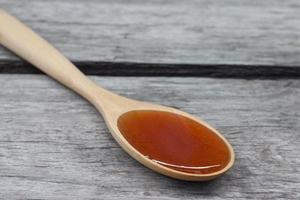 le miel dans une cuillère en bois a un goût sucré sur fond de table en bois vintage. photo