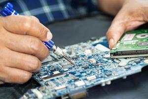 technicien réparant l'intérieur de la carte de circuit imprimé en fer à souder. circuit intégré. le concept de données, de matériel, de technicien et de technologie. photo