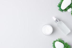 produits cosmétiques de soins de la peau avec des pierres et de la mousse sur fond gris. mise à plat, espace de copie photo