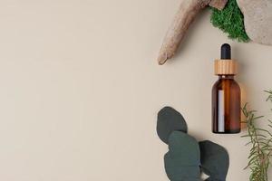 bouteille cosmétique avec bois et mousse sur fond naturel beige. mise à plat, espace de copie. photo