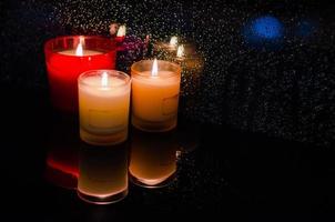 bougies en verre placées à côté de la fenêtre qui a des gouttes de pluie sur fond sombre. photo