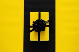 une boîte cadeau jaune avec ruban noir met sur fond noir et jaune. concept de vendredi noir et de boxe. photo