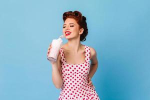 fille inspirée en robe à pois buvant du milkshake. modèle féminin de gingembre riant tenant une boisson photo