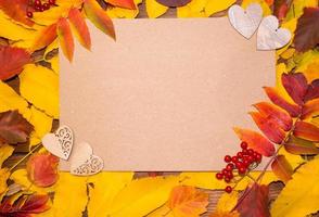 Bonjour octobre. composition d'automne, vue de dessus des feuilles d'automne aux couleurs vives avec une feuille de papier et deux coeurs en bois. espace pour le texte photo