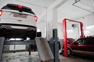 voiture suv américaine sur support pour l'alignement des roues contrôle de carrossage dans l'atelier de la station-service. photo