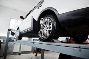 voiture suv américaine sur support pour l'alignement des roues contrôle de carrossage dans l'atelier de la station-service. photo