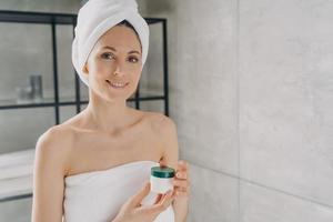 femme tenant un pot de cosmétiques maquette avec de la crème, publicité pour un produit de beauté de soin de la peau dans la salle de bain photo