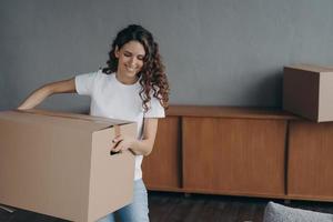 femme heureuse portant une boîte en carton avec des choses, déménageant dans la première nouvelle maison. hypothèque, déménagement photo