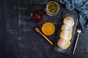 délicieux syrniki maison avec confiture de fraises et miel. plat traditionnel russe syrniki. vue de dessus photo