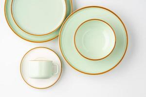 un ensemble de vaisselle en céramique blanche et vert pastel aux contours orange. vue de dessus photo