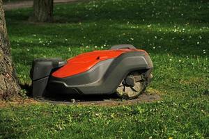 tondeuse à gazon robotique sur fond d'herbe verte.tondeuse à gazon robot automatique dans un jardin moderne.coupe d'herbe verte avec tondeuse à gazon. vue rapprochée de la lame sale de la tondeuse à gazon après avoir tondu la pelouse. photo