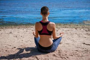 jeune femme mince faisant du yoga à l'extérieur sur la baie de rivage sablonneux par une journée ensoleillée. unité photo