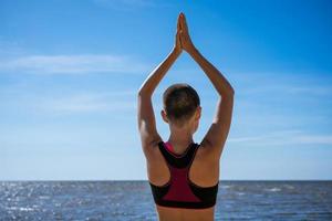 jeune femme mince faisant du yoga à l'extérieur sur la baie de rivage sablonneux par une journée ensoleillée. unité photo