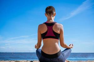 jeune femme mince faisant du yoga à l'extérieur sur la baie de rivage sablonneux par une journée ensoleillée. unité photo