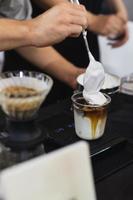 barista faisant du café au lait glacé avec fouet à la main dans le café. photo