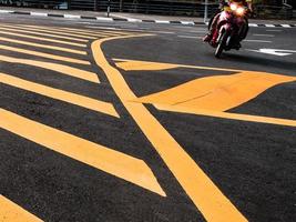 vue en angle bas d'un motocycliste passant devant le marquage routier jaune photo